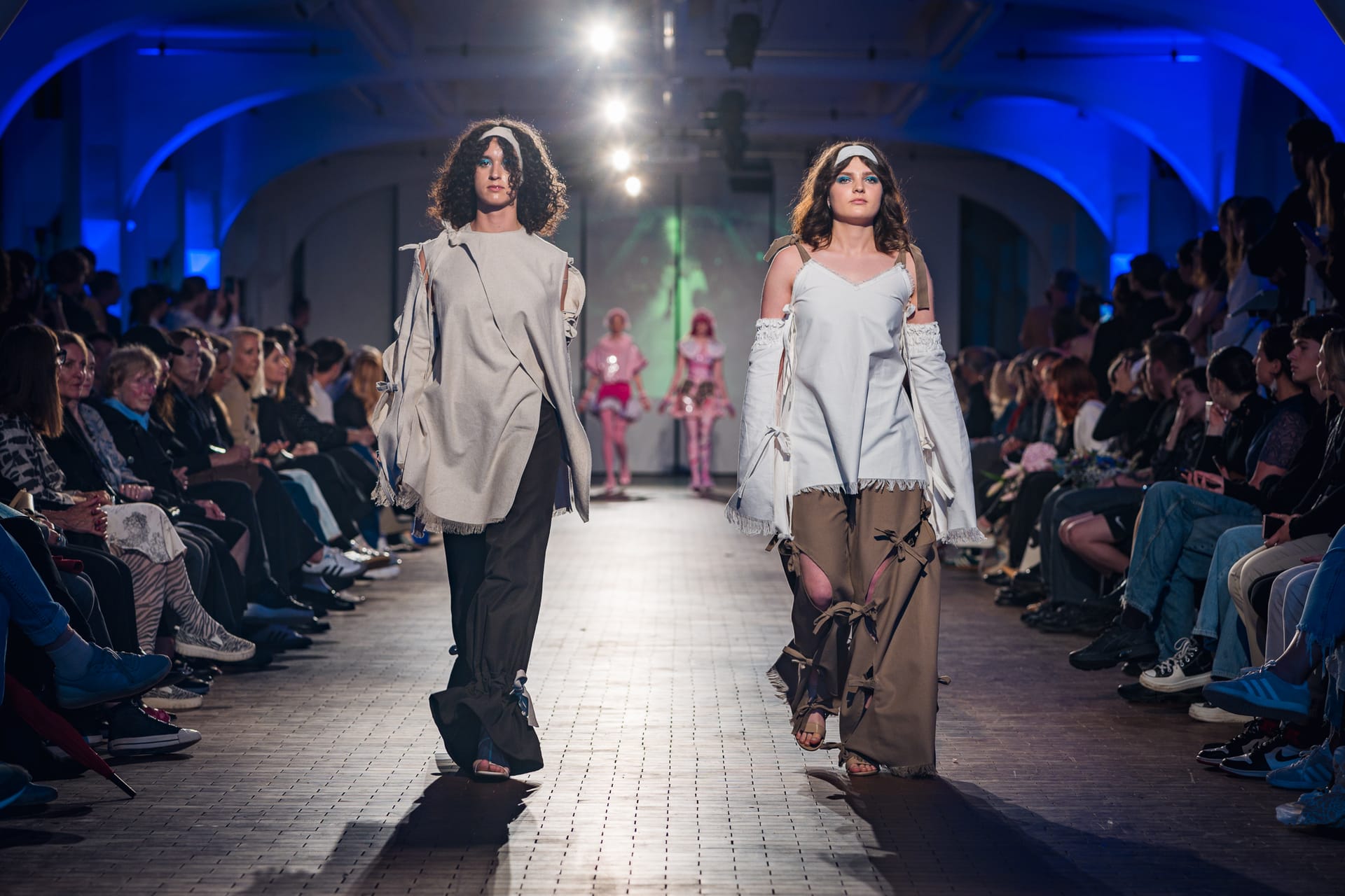 Two models walking a runway in deconstructed, earthy-toned garments